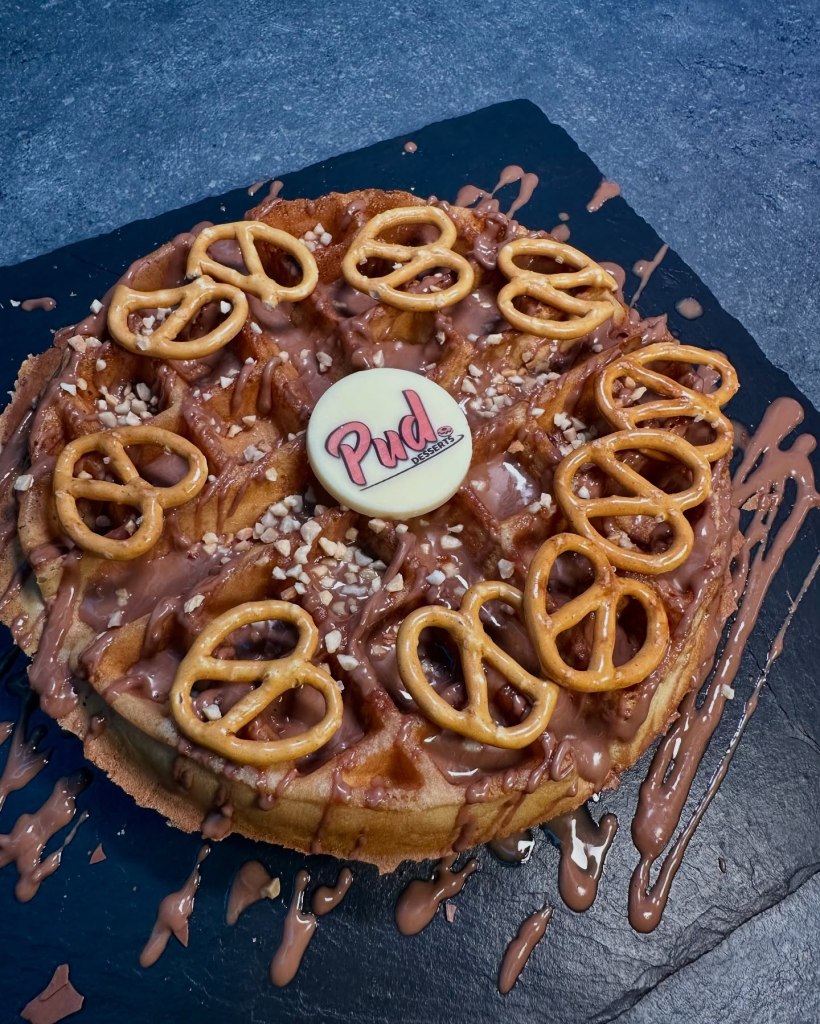 Warm waffle topped with melted chocolate, crunchy pretzels, and served with creamy gelato ice cream