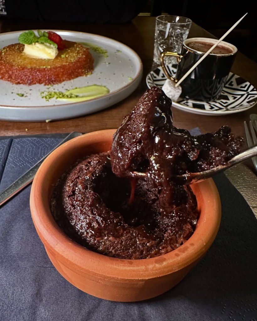 A decadent chocolate soufflé with molten center, served with a scoop of creamy vanilla gelato on a sleek black plate