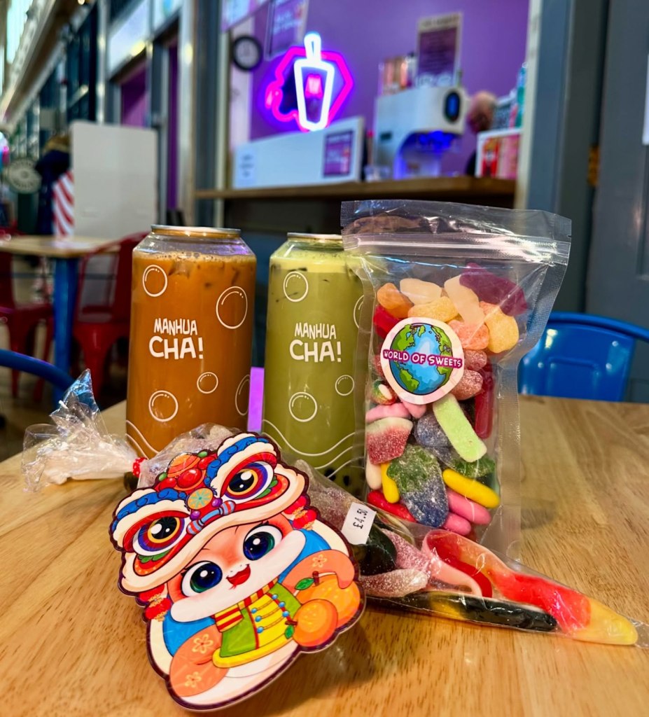 An assortment of bubble tea cans, pick and mix sweets, and DIY kits displayed on a counter, showcasing a variety of vibrant colors, textures, and flavors.
