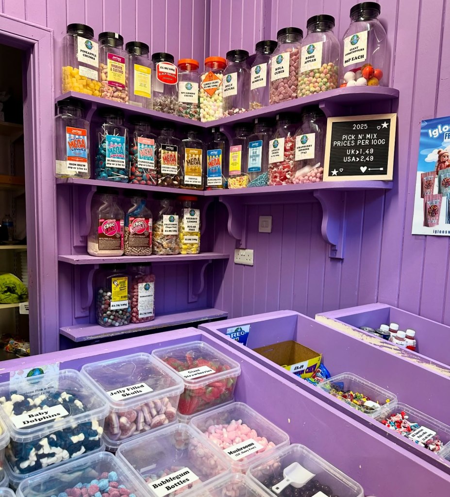 A cozy stall in the Grainger Market with bright signage, neatly stacked jars of sweets, and a modern bubble tea preparation area.