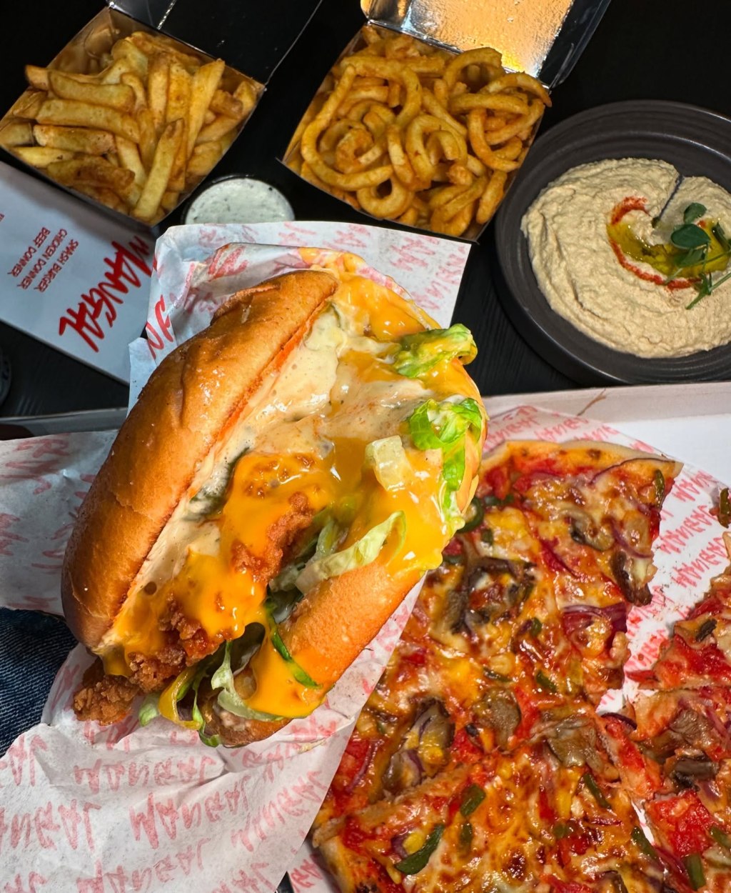 A crispy chicken burger glazed with hot honey, topped with fresh chilies, cheese, and pickles, served in a fluffy bun.