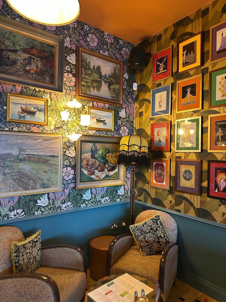 An eclectic interior at Cantoro Lounge featuring vibrant, mismatched decor with colorful artwork on the walls, cozy seating areas, and warm ambient lighting.