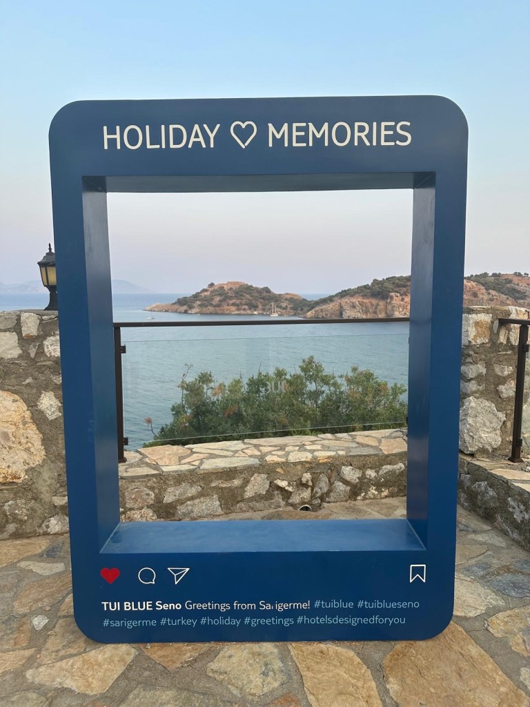 Breathtaking view from TUI Blue Seno overlooking the turquoise coast with a picturesque island on the horizon, framed by the golden hues of a Mediterranean sunset.