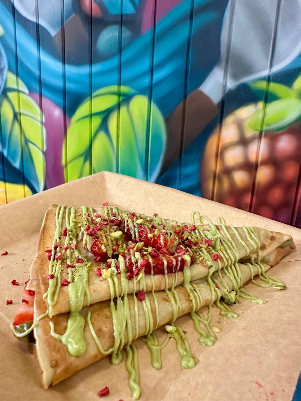 A beautifully presented sweet crepe with Sicilian pistachio spread, crushed pistachios, fresh strawberries, and a sprinkle of raspberry flakes.