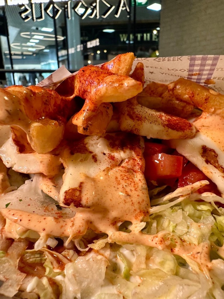 A freshly made chicken gyros wrap, filled with juicy grilled chicken, crispy fries, fresh salad, and Acropolis’ signature sauce, all wrapped in a soft, warm pita.