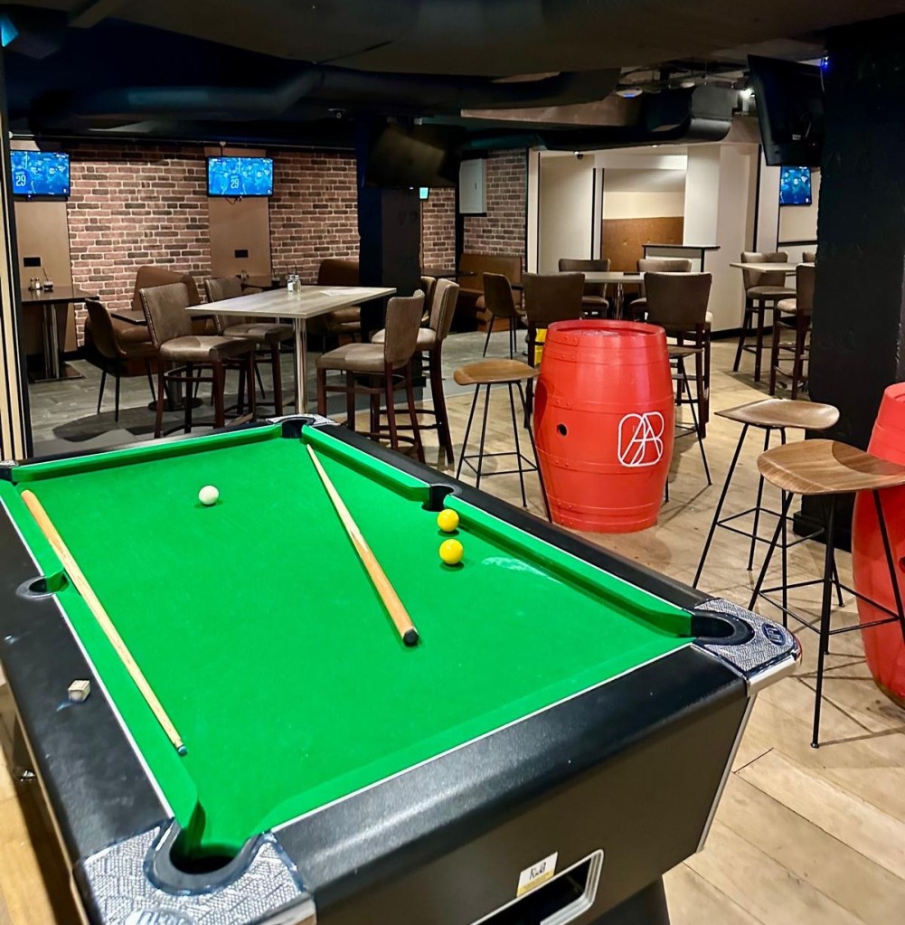 A pool table at Abajo sports bar in Newcastle, set against a backdrop of industrial-chic decor