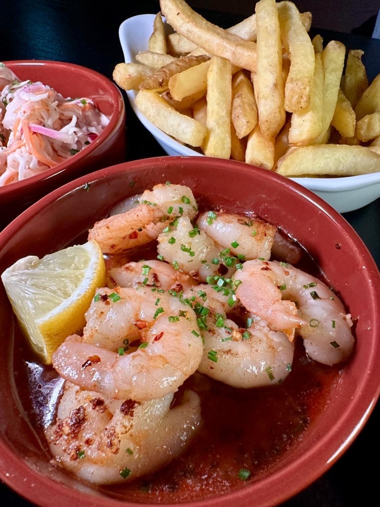 A tapas dish of Gambas Pil Pil featuring king prawns cooked in garlic, chilli, and paprika