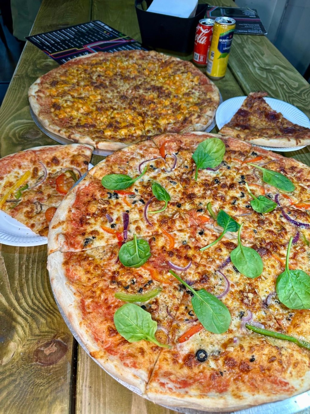 A gourmet truffle-infused New York-style pizza topped with mozzarella, red onion, walnuts, and spinach on a tomato base.