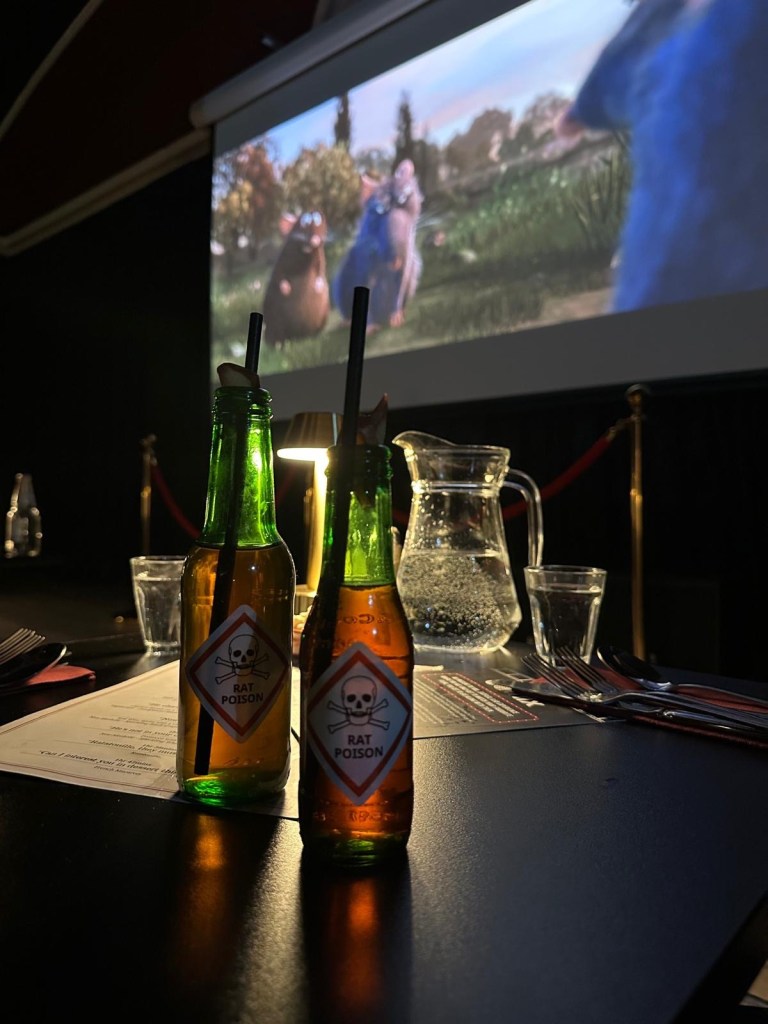 A vibrant red Poison Apple cocktail served in a stylish glass, garnished with fruit.