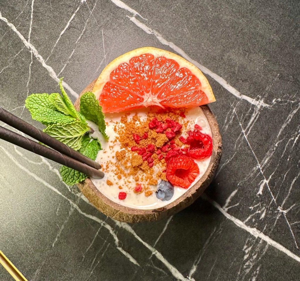 A beautifully presented Pina Colada served in a coconut shell with fresh fruit garnish.