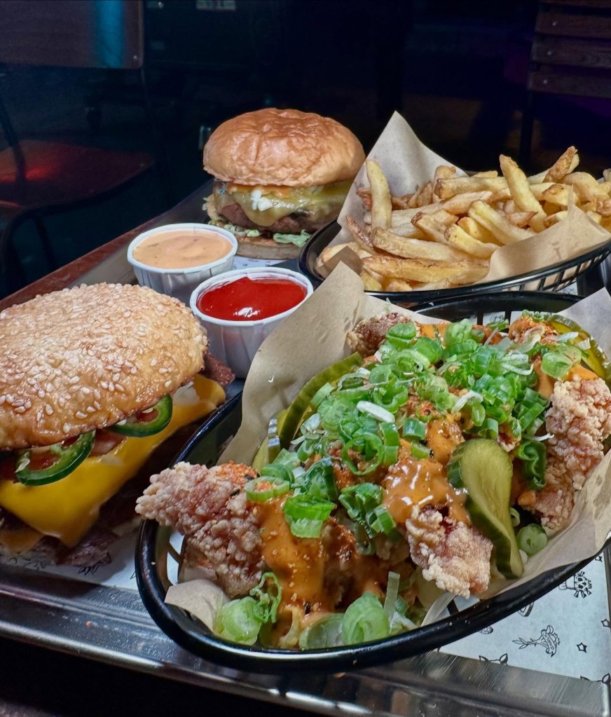 A spread of Pattymelts' top menu items, including stacked burgers, crispy fries, hot fried chicken, house sauce, and burnt Basque cheesecake.