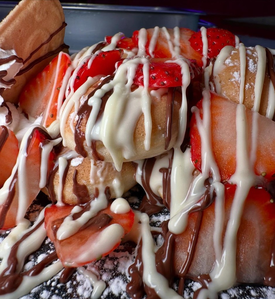 Fluffy waffle bites covered in chocolate and fresh strawberries, served with cream on the side