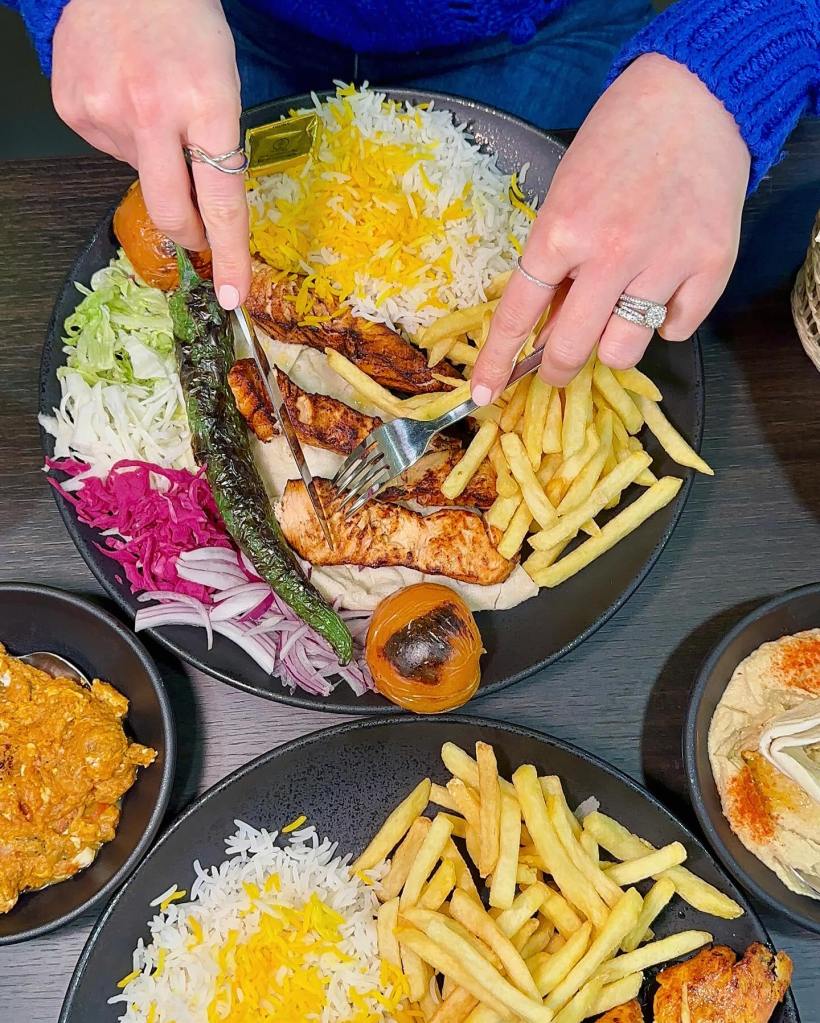 A plate of chargrilled salmon with crispy skin, served with grilled vegetables and fresh salad.