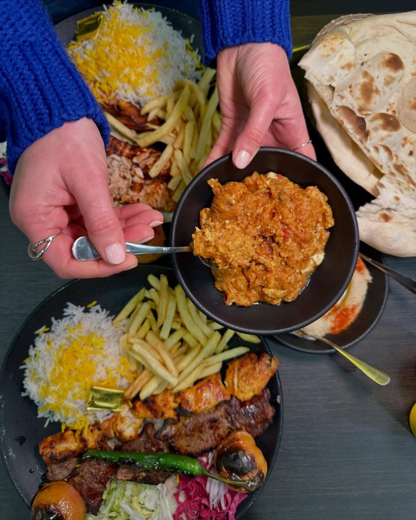 Chargrilled aubergine with a smoky texture, served alongside freshly baked naan on a white plate.