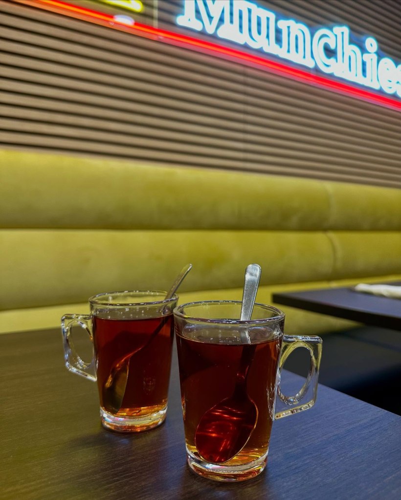 A glass of Persian chai served in a traditional cup with a side of sugar cubes.