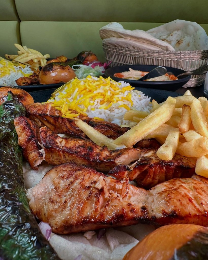 A plate of chargrilled salmon with crispy skin, served with grilled vegetables and fresh salad.