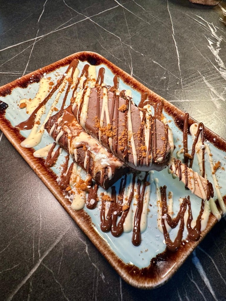 A decadent, fudgy chocolate brownie topped with a mini Magnum ice cream and drizzled with chocolate sauce.
