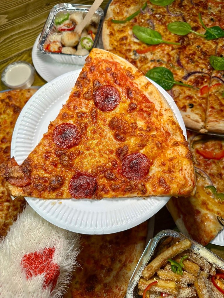 A classic New York-style pepperoni pizza slice with a thin, crispy crust, topped with rich tomato sauce, gooey mozzarella, and spicy pepperoni, finished with a sprinkle of oregano.