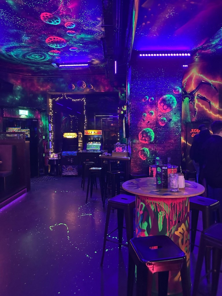 A sleek cocktail bar illuminated by neon lights, serving gaming-inspired drinks with a retro arcade ambiance at NQ64 Newcastle.
