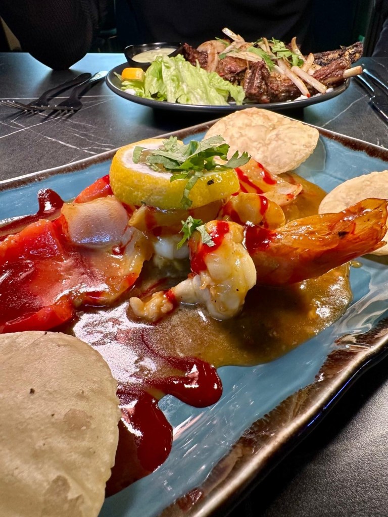 Chargrilled king prawns served on a sizzling platter with grilled vegetables and a side of fragrant rice.