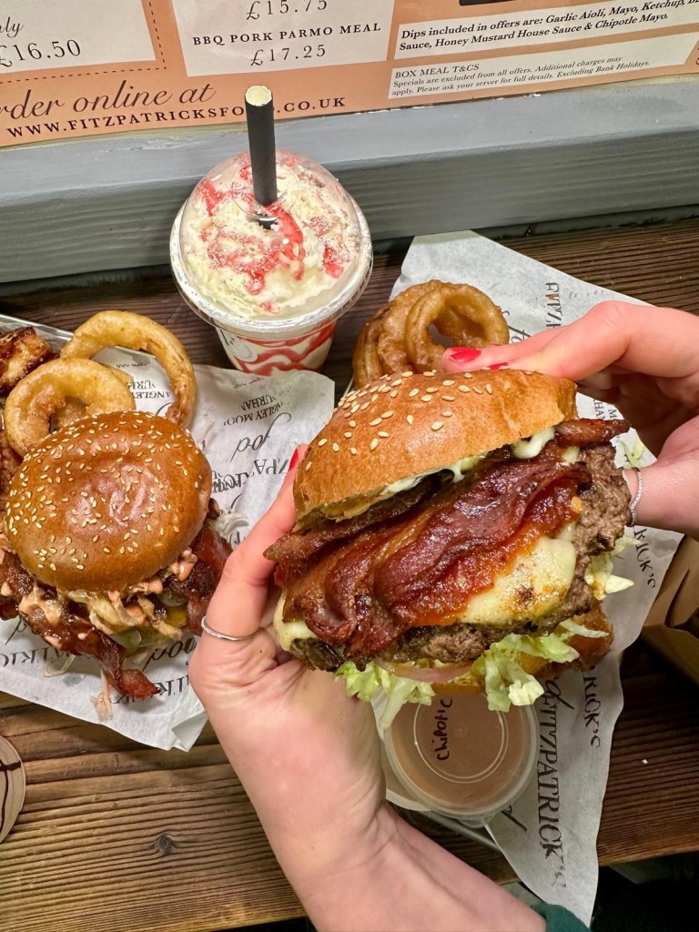 A towering Garlic Steak Burger with Swiss cheese, crispy bacon, garlic aioli, and pickled onions, served on a toasted brioche bun.