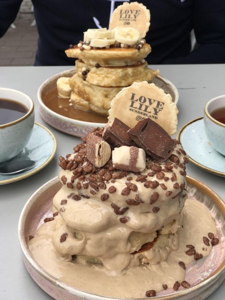 A fluffy stack of protein pancakes drizzled with syrup and topped with chocolate