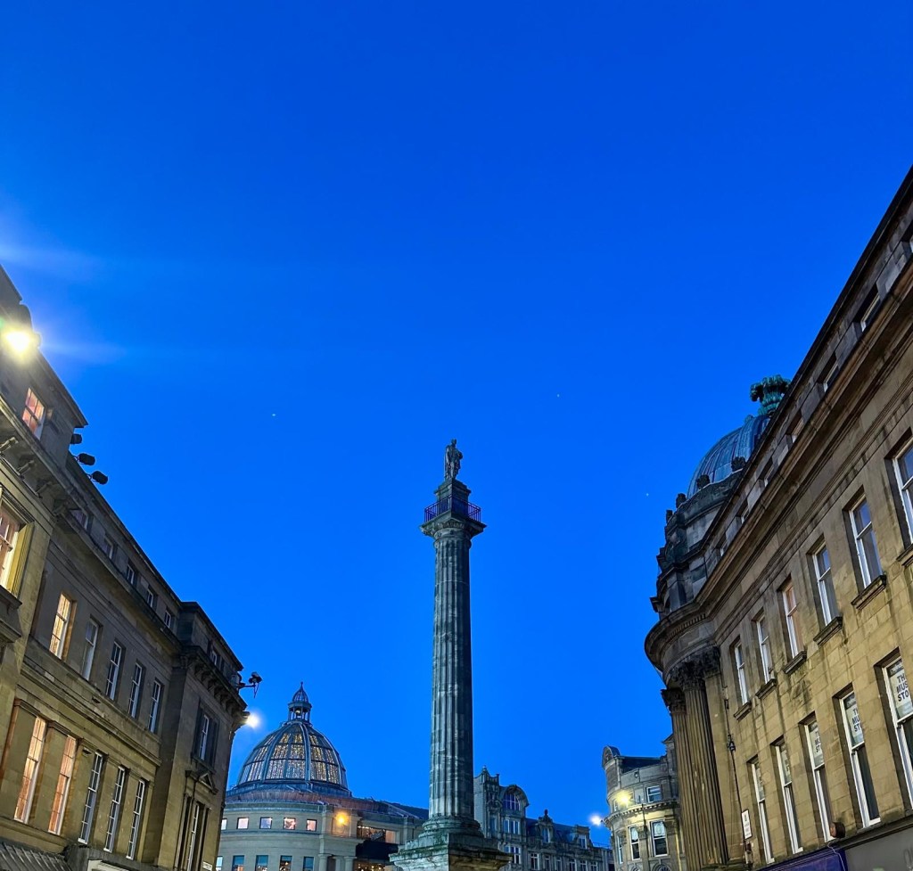 Grey’s Monument towering over Newcastle’s city center with a bright blue sky in the background