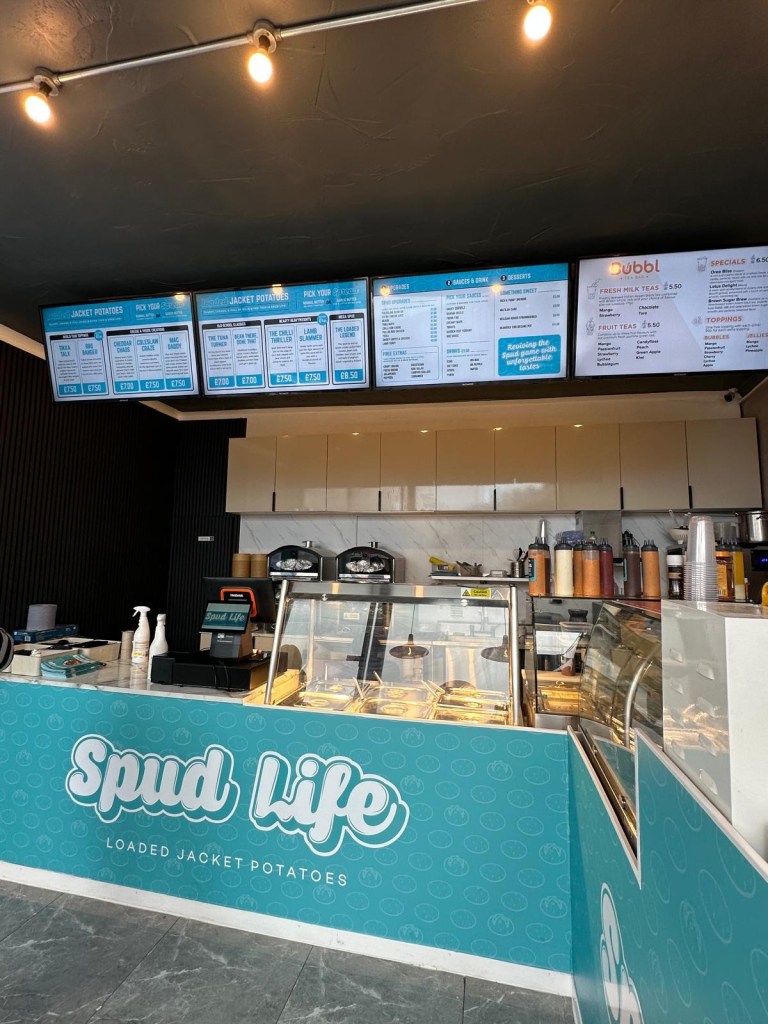 The interior of Spud Life Newcastle, featuring a modern and inviting space with bright décor, seating areas, and a counter displaying fresh ingredients.