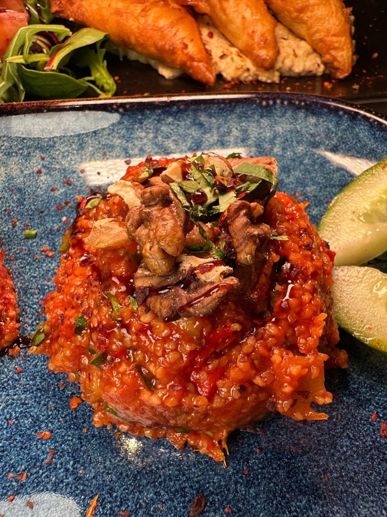A vibrant Turkish kisir salad made with bulgur wheat, crushed walnuts, tomatoes, and fresh herbs, served in a small dish.