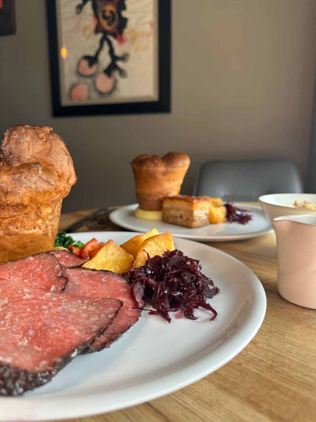 Slices of tender roast beef with a giant Yorkshire pudding, crispy roast potatoes, and colorful seasonal vegetables.
