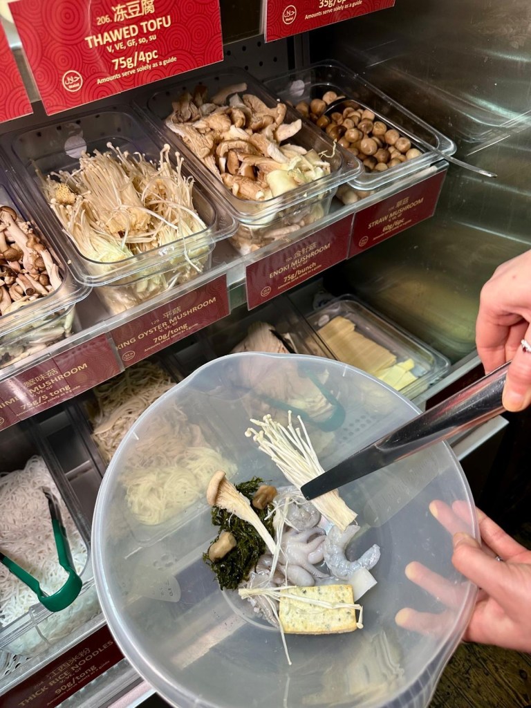Two bowls filled with a variety of fresh Malatang ingredients, including vegetables, seafood, meats, and noodles, ready to be cooked.