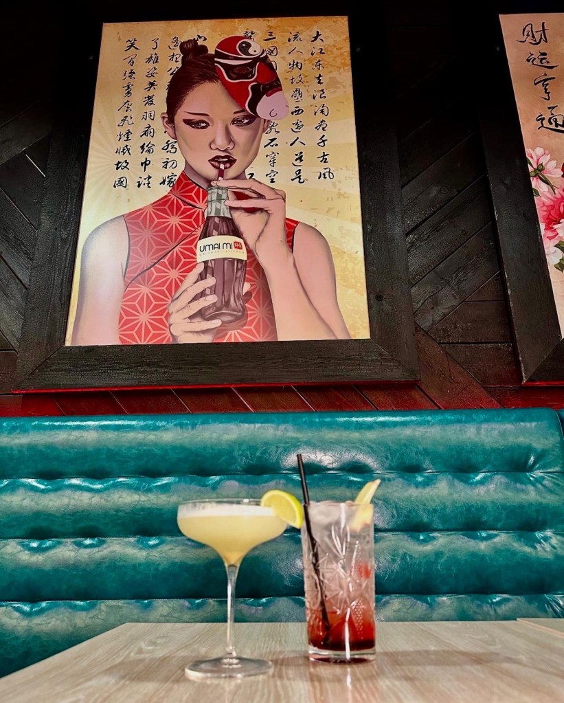 A Wasabitini cocktail with a citrus twist alongside an Orchid Twilight softail, elegantly presented with fresh fruit garnishes.