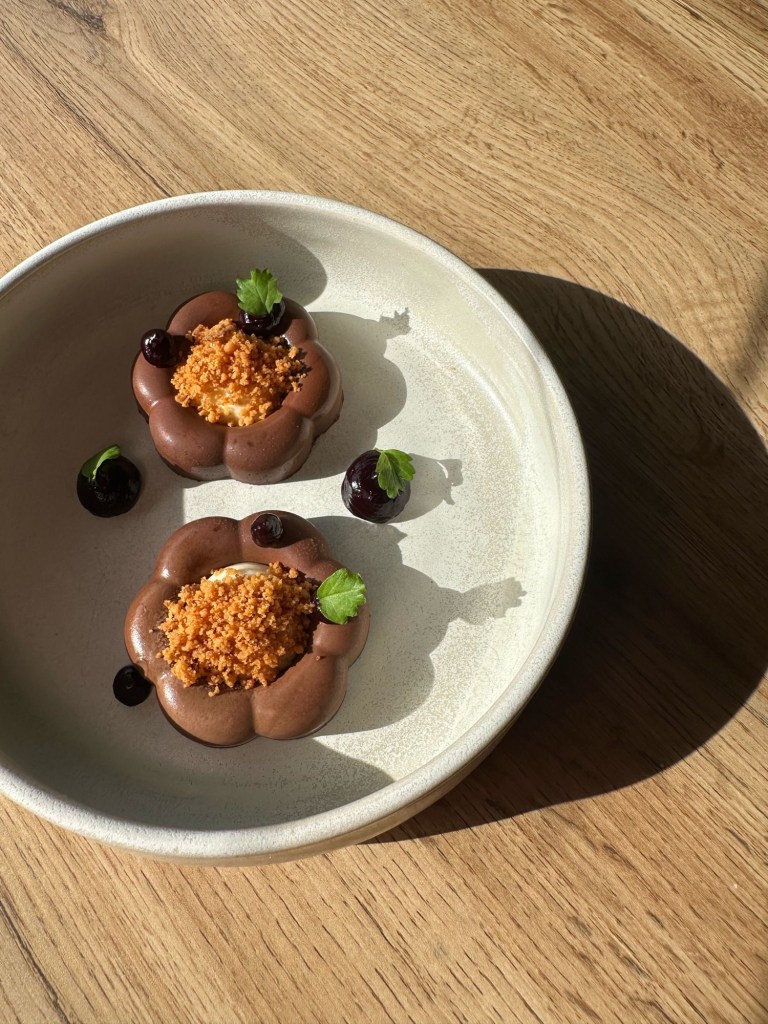 A rich chocolate cremeux with glossy cherry gel, served with a delicate baked cheesecake and crunchy cookie crumb.