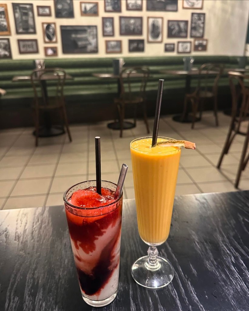 A chilled mango lassi in a tall glass, topped with saffron strands and crushed pistachios.