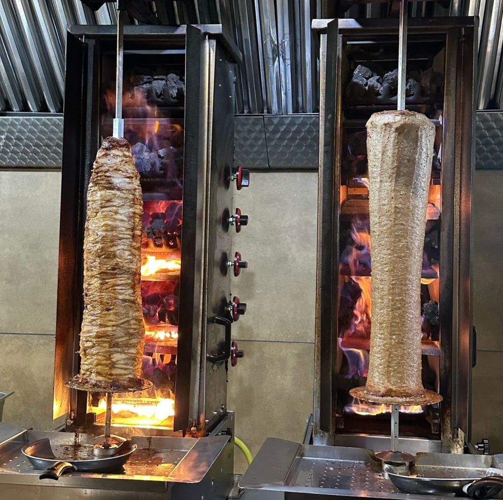 Doner meat roasting on an open flame at This is Doner