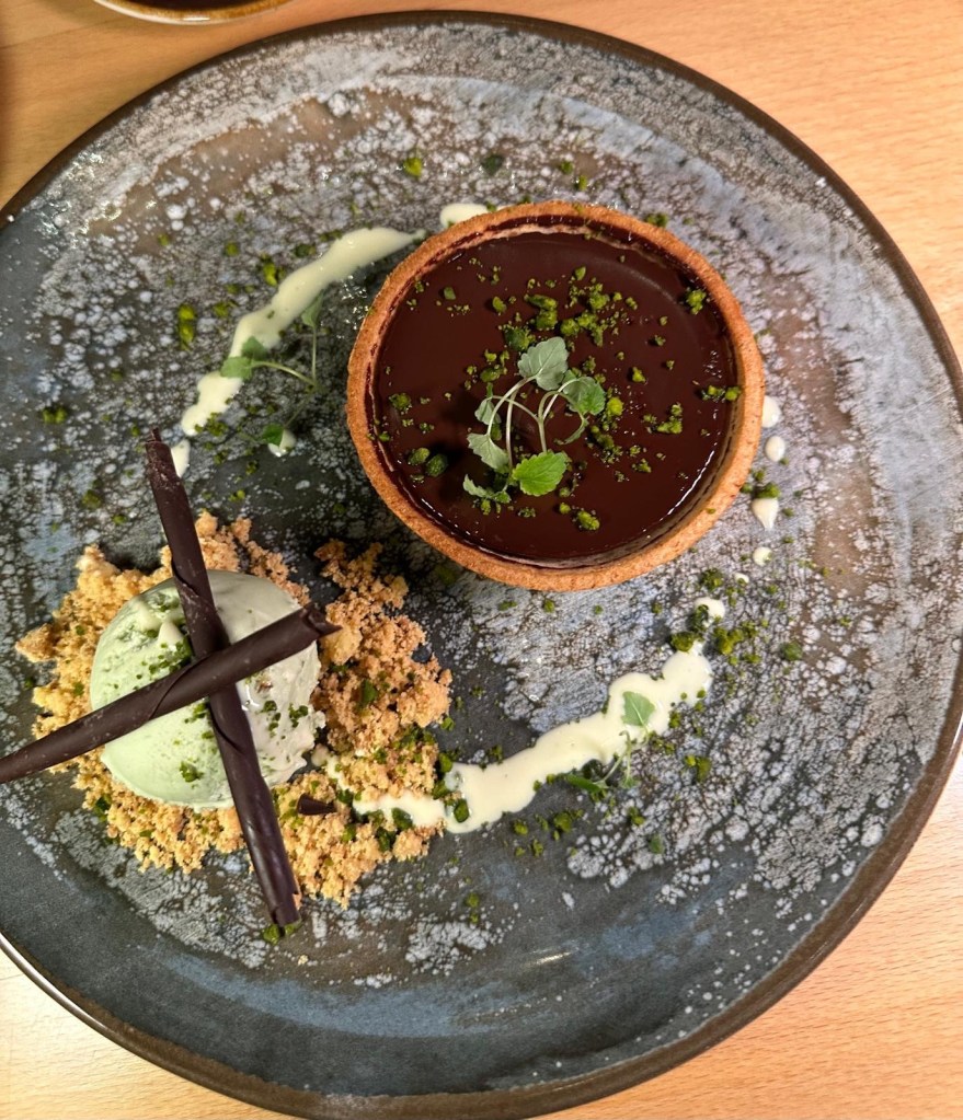 A decadent extra bitter chocolate tart served with a scoop of creamy pistachio ice cream.