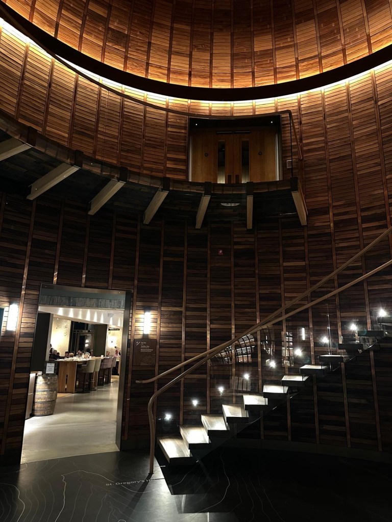 A breathtaking interior featuring elegant light fixtures suspended from a grand dome ceiling, with a striking hardwood circular staircase leading upwards.