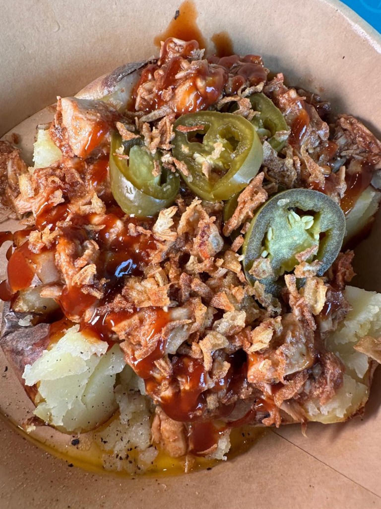 The BBQ Banger baked potato at Spud Life Newcastle, featuring pulled chicken in smoky BBQ sauce, crispy onions, and fresh herbs.