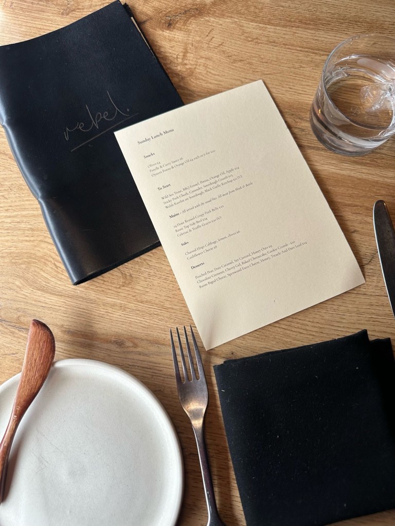 A beautifully set restaurant table featuring a stylish menu, elegant tableware, and a cosy dining atmosphere.