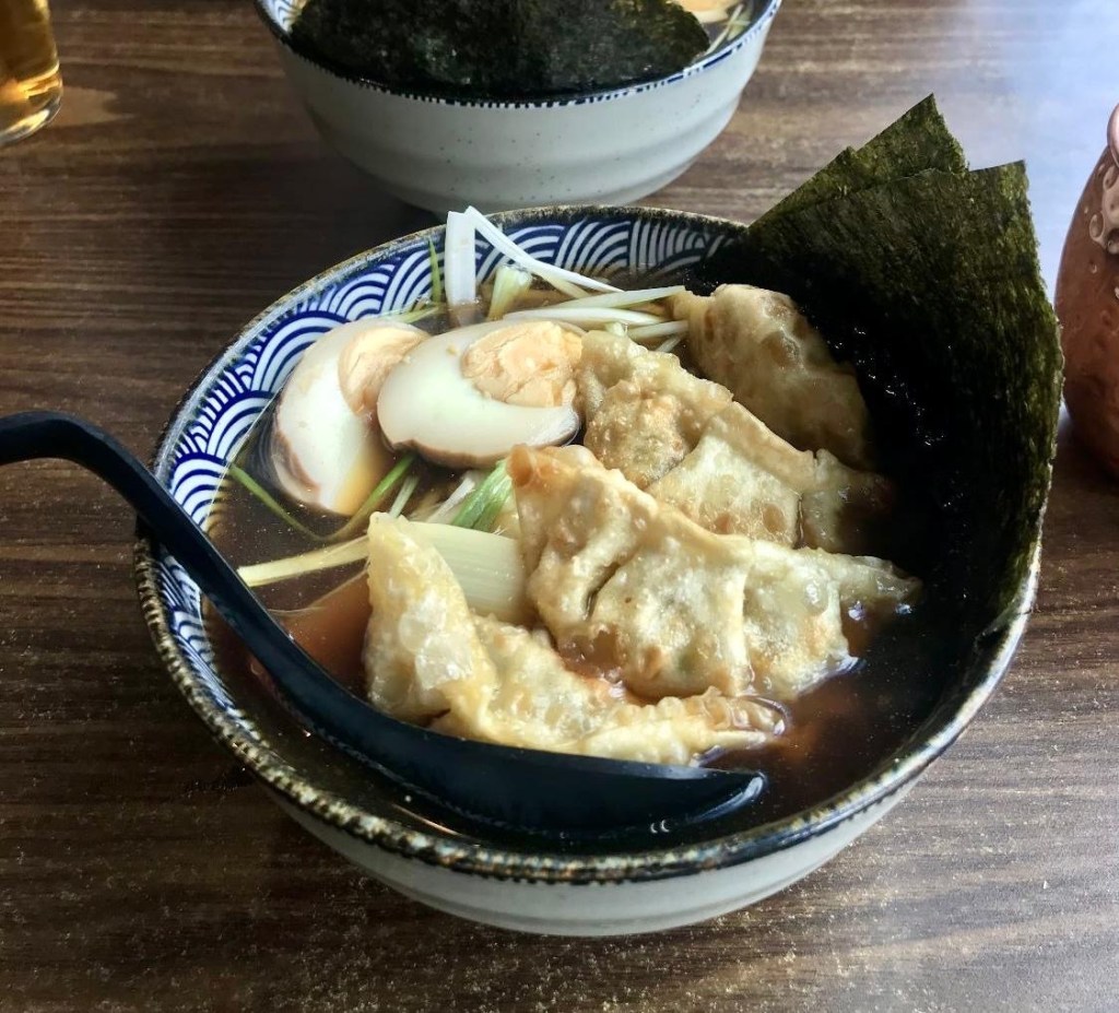 A vibrant poke bowl filled with fresh ingredients, served alongside crispy golden-brown pot stickers.