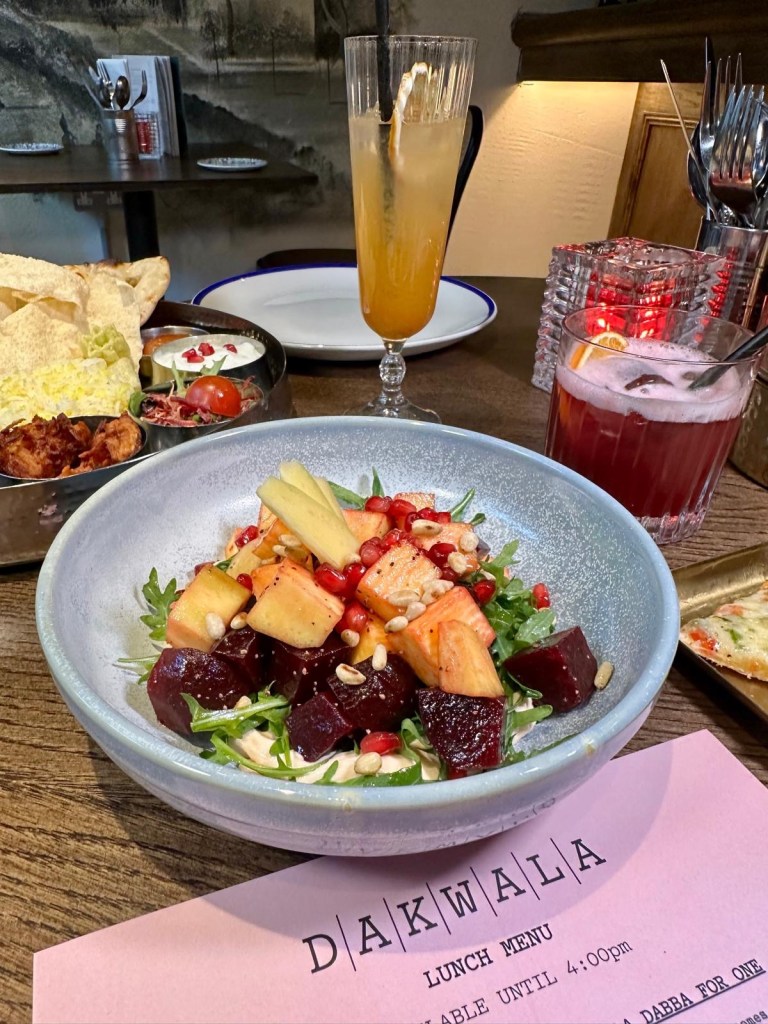 A vibrant salad with fresh mango slices, beetroot, crisp salad leaves, pomegranate seeds, and a creamy yogurt base.