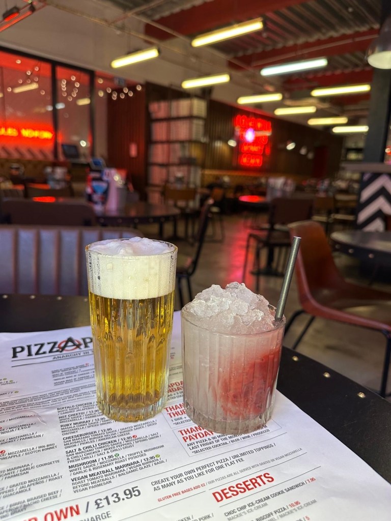 A vibrant cocktail and a cold beer served together at Pizza Punks.