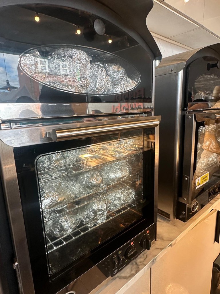 Large ovens filled with foil-wrapped baked potatoes cooking to perfection at Spud Life Newcastle.