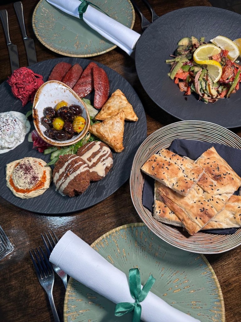 A platter of assorted Turkish starters, including sucuk, falafel, muska böreği, hummus, beetroot salad, cacik, and olives at Lezzet Newcastle