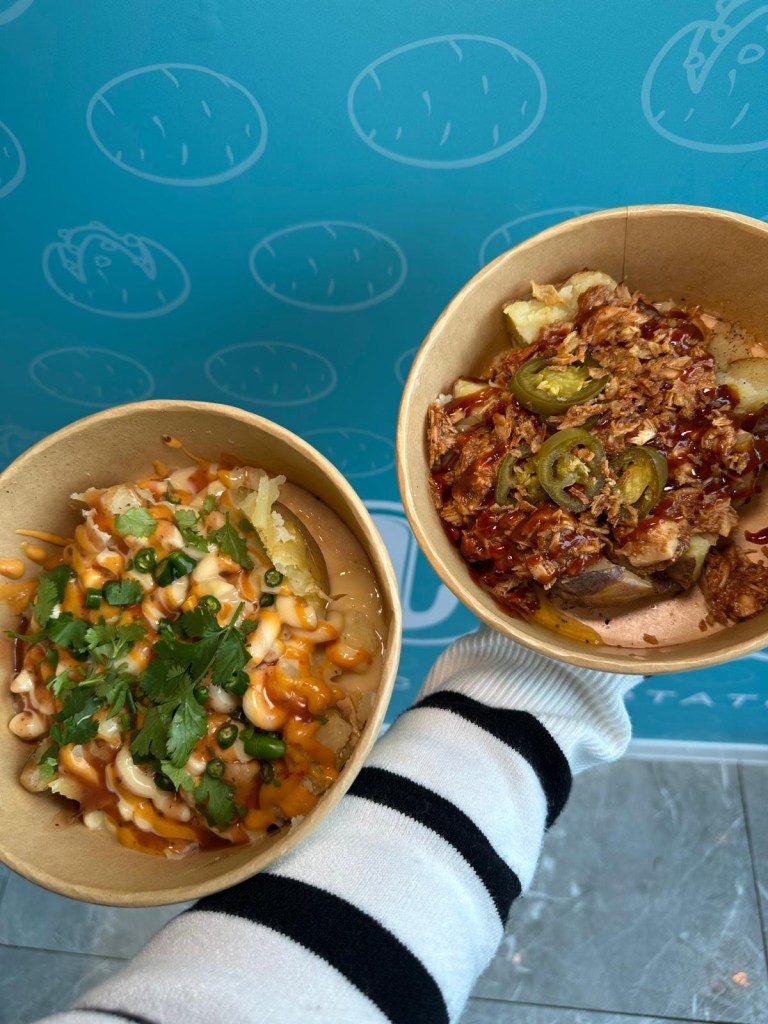 A selection of fully loaded baked potatoes from Spud Life Newcastle, featuring toppings like mac and cheese, pulled chicken, crispy onions, and BBQ sauce.