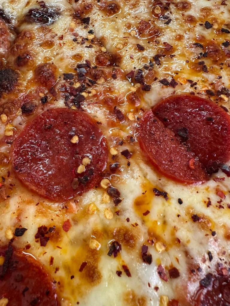 A 20-inch New York-style pizza with crispy, thin crust, topped with spicy pepperoni, gooey melted cheese, and a drizzle of sweet honey.