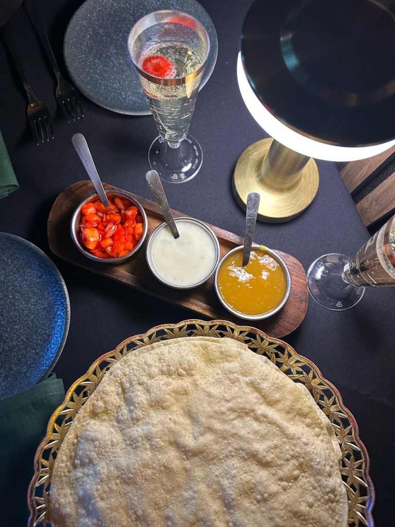 A traditional Indian pickle tray with crispy poppadoms, chutneys, and dips at Chester’s Lounge.