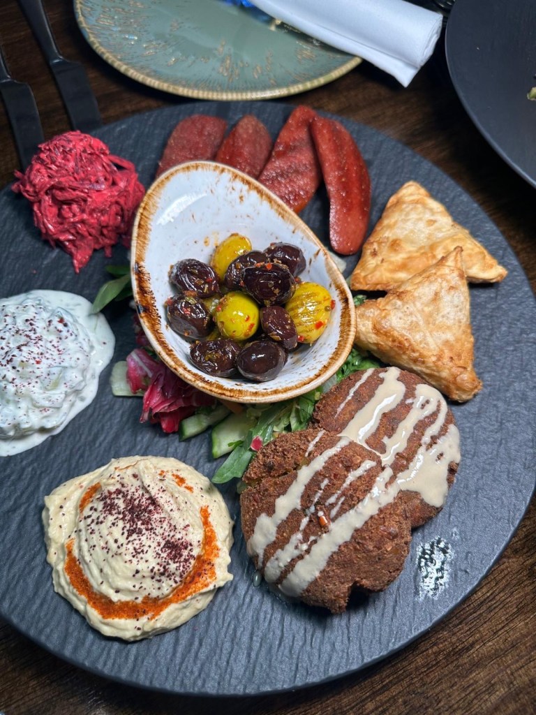 Lezzet Newcastle's Assorted Mix Platter with sucuk, falafel, muska böreği, hummus, beetroot salad, cacik, and olives.