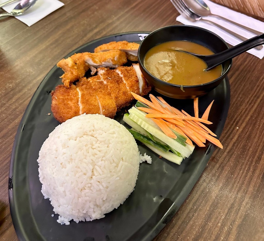 A plate of crispy breaded chicken breast served with rich katsu curry sauce and steamed jasmine rice.