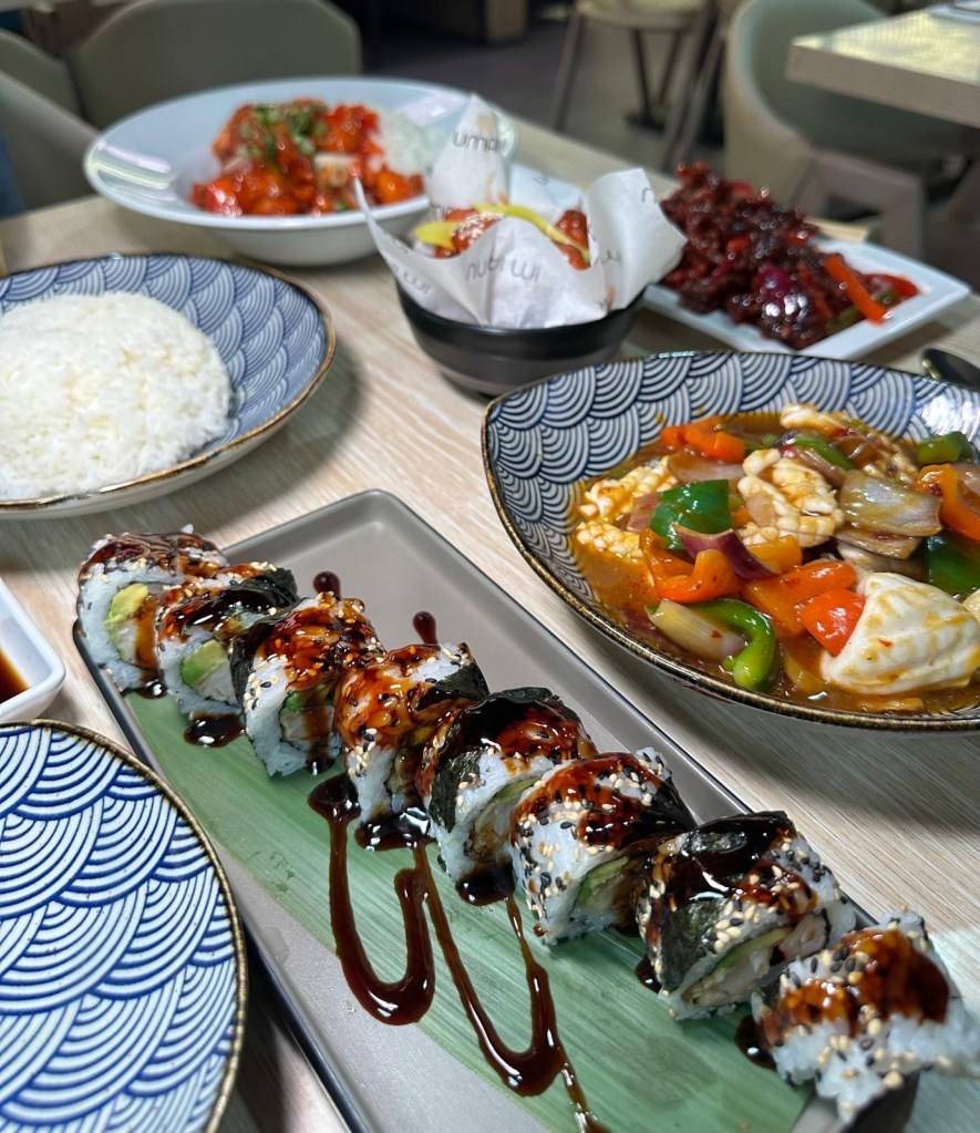 A plate of prawn tiger roll sushi, elegantly arranged with drizzles of sauce and delicate garnishes.